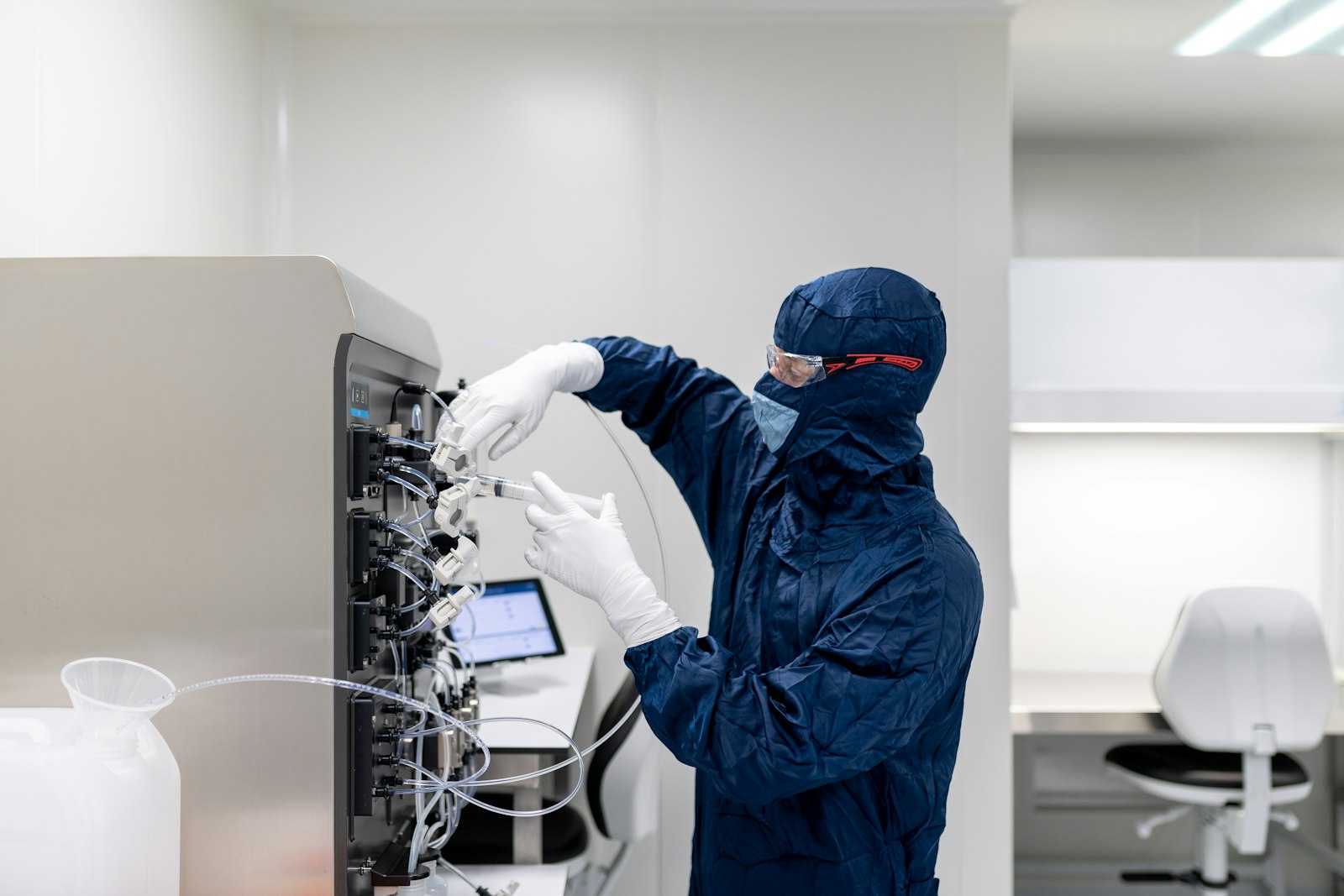 A researcher in a cleanroom suit operating lab instrumentation